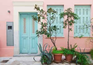 Pastel pink building with light blue door, shutters and green tr